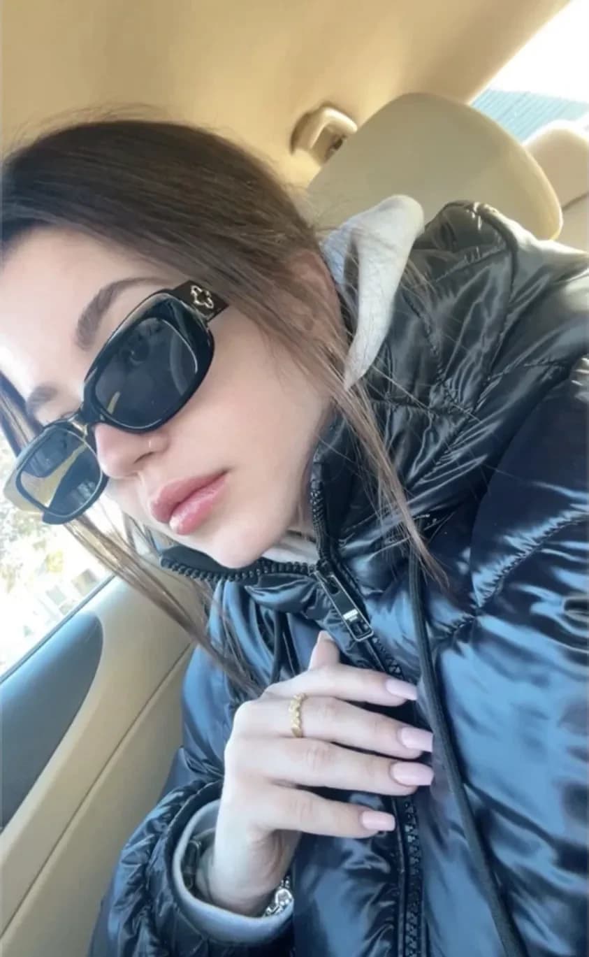 Kind em uma selfie no carro, de óculos escuros e jaqueta preta